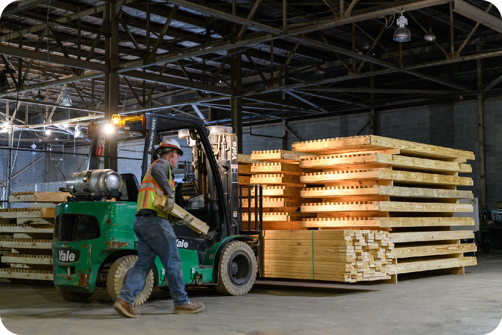 Construction work and a man carry wood towards a wood pile