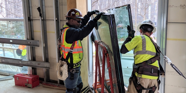 Installation of triple pane windows. Both half-inch spaces between the three quarter-inch panes are filled with argon gas, which has greater insulating qualities than air.